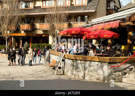 Menschen genießen die Whistler Village in Straßencafés und Restaurants an einem sonnigen Tag im Frühjahr.  Whistler, BC, Kanada Stockfoto