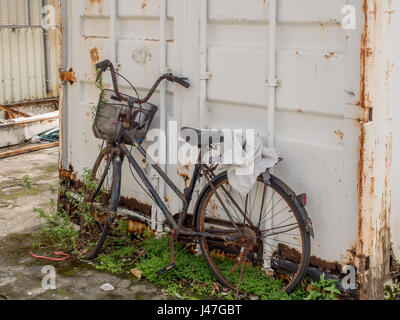 Taipeh, Taiwan - 16. Oktober 2016: Schwarz, zerstörte Fahrrad mit einem weißen Garagentor in einen Hintergrund auf den Straßen von Yilan Stockfoto