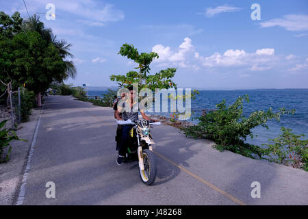 Männer fahren mit dem Motorrad am Ufer des Sees Peten Itza in der Stadt San Andres in der Region des Peten Basin im Norden Guatemalas Stockfoto