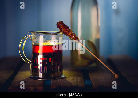 Das Glas mit Halter voller heißer, schwarzer Tee auf der Holzoberfläche Stockfoto