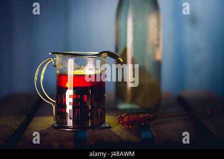 Das Glas mit Halter voller heißer, schwarzer Tee auf der Holzoberfläche Stockfoto