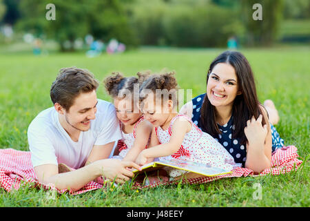 Eine glückliche Familie liest Buch im park Stockfoto