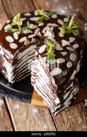 Stück Schokolade Krepp-Kuchen mit geschlagener Sahne und Mandeln Nahaufnahme auf eine vertikale Tabelle Stockfoto