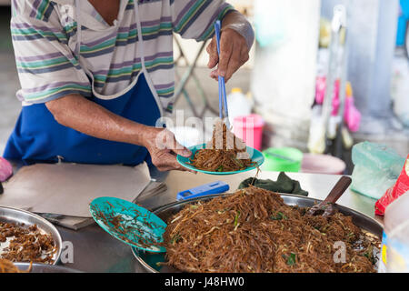 GEORGE TOWN, MALAYSIA - 23. März 2016: Senior woman gebratene Nudeln auf Kimberly Street Food Nachtmarkt am 23. März 2016 in George Town, Mal verkauft Stockfoto