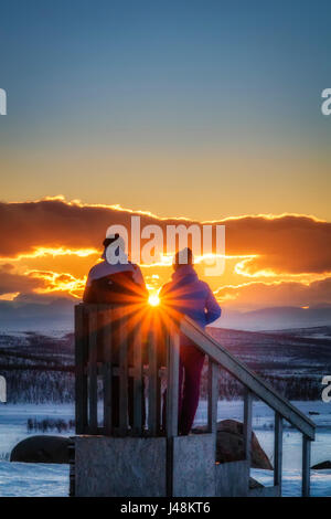 Paar genießt einen Winter Sonnenuntergang, Lappland, Schweden Stockfoto