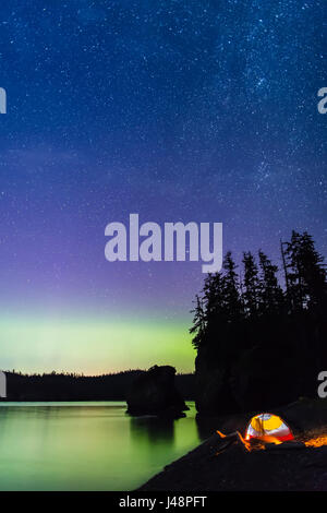 Eine leuchtende Zelt am Strand mit Blick auf grün, die Aurora Borealis im ruhigen Meereswasser, Hesketh Insel spiegeln; Homer, AK, USA Stockfoto