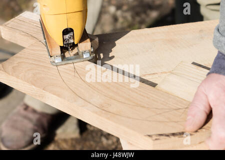 Zimmermann ist eine Bogenform aus Holzbrett mit Laubsäge ausschneiden. Möbelbau. Stockfoto