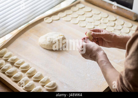Frau Wareniki oder Knödel Pierogi an Holz Bord vorbereiten, kochen. Koch bereitet traditionellen ukrainische Küche. Mutter macht leckeres Gericht für Stockfoto