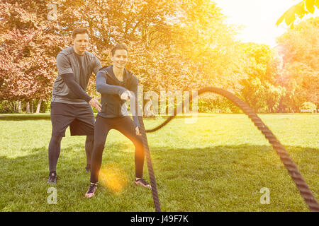 Frau in Schlacht Seil Fitnesstraining mit Personal Trainer Stockfoto