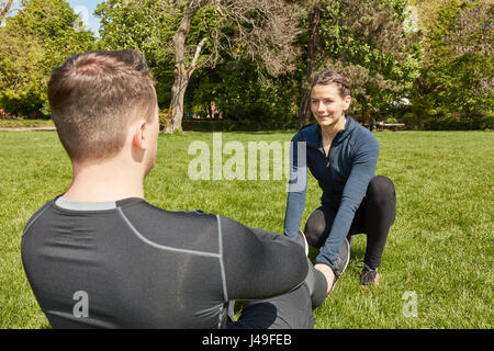 Mann macht Sit-ups im Park mit Fitness Training Trainer Stockfoto