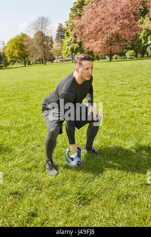 Sportlichen Mann macht Crossfit mit Kettlebell im park Stockfoto