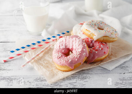 Donuts mit Glas Milch auf Holztisch Stockfoto