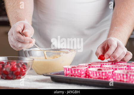 Papier-Muffin Fällen Erfülltsein mit Teig für Kirsch-Schokoladen-muffins Stockfoto