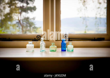 Raffinierte Landleben - fünf stilvolle kleine Glasflaschen, die auf einem Fensterbrett sitzen Stockfoto