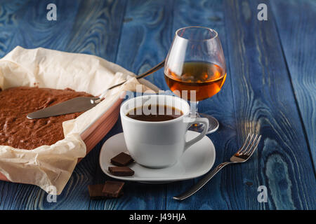 Frisch gebackene Schokoladen-Brownie in quadratischen Backblech mit Papier auf rustikalen hölzernen Hintergrund. Dunkle Essen Foto mit flachen Fokus Stockfoto