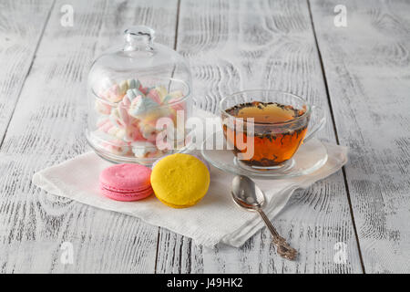 Bunte Makronen mit Tasse Tee auf Farbe Holztisch, auf hellem Hintergrund Stockfoto