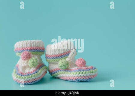 Neugeborenen Ankündigung. gestrickte Babyschuhe auf einfachen Aquamarin Hintergrund Stockfoto