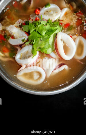 Thai-Food, ring Tintenfisch in würzige Suppe mit schwarzem Hintergrund Stockfoto