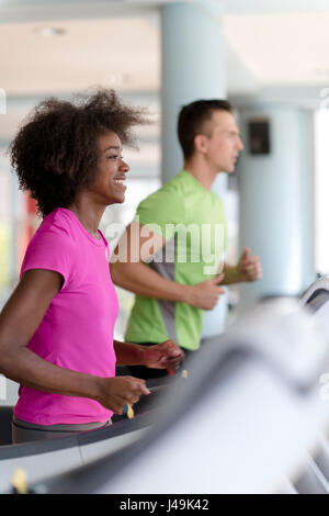 junge Leute Exercisinng Cardio am Laufband läuft Maschine im modernen Fitnessraum Stockfoto