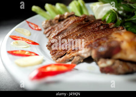 Gebratenes Schweinefleisch mit Gemüse in schwarzen Hintergrund Stockfoto