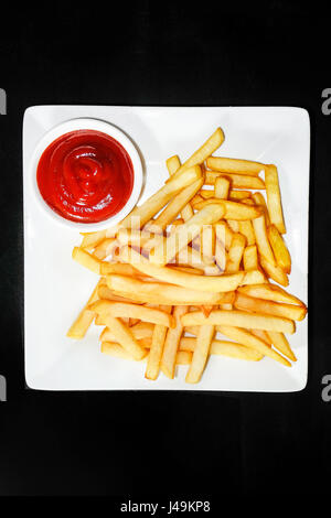 ein Haufen von leckeren Pommes Frites auf einem schwarzen Hintergrund Stockfoto