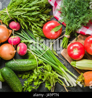 Frisches Gemüse und grünen Trauben in einem Frame auf einem schwarzen Stein Hintergrund angeordnet. Draufsicht mit Platz für Text. Stockfoto