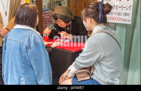 Nagasaki, Japan - März 26., 2017: Eine reife japanische Frau liest die Linien der Hände von einem Kunden auf einer Fußgängerzone in Chinatown, nagasak Stockfoto