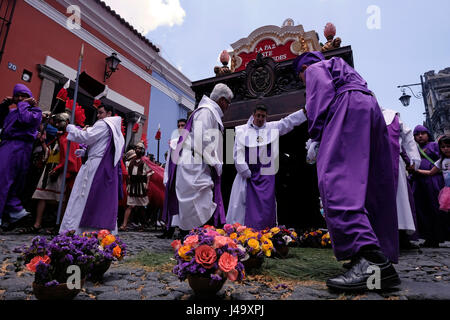 Männer gekleidet in lila Roben tragen die Anda (Float) von Jesus das Kreuz zu tragen, während der Semana Santa oder Heilige Woche Feier in der Stadt Antigua Guatemala Stockfoto