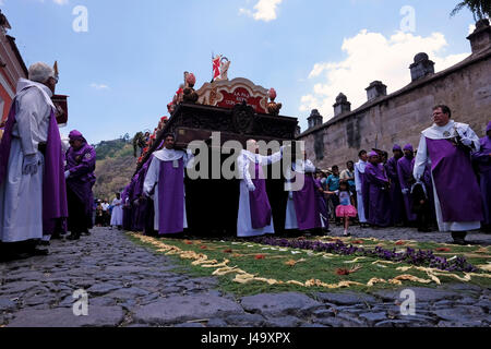 Männer gekleidet in lila Roben tragen die Anda (Float) von Jesus das Kreuz zu tragen, während der Semana Santa oder Heilige Woche Feier in der Stadt Antigua Guatemala Stockfoto