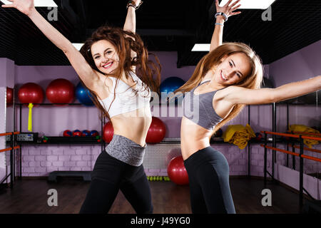 Zwei aufgeregt Fitness Mädchen springen im Gesundheitszentrum. Lachende junge glückliche Frauen haben Spaß in der Turnhalle Stockfoto