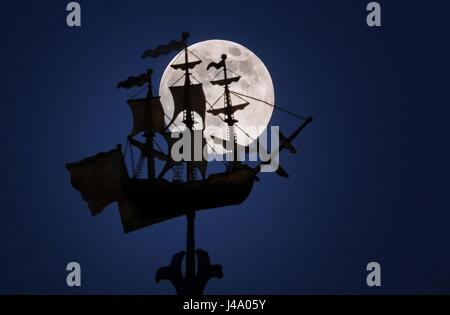 Vollmond, bekannt als Blume Mond im Monat Mai, erhebt sich hinter den vergoldeten Schiff Wetterfahne George Watsons College, Edinburgh. Stockfoto