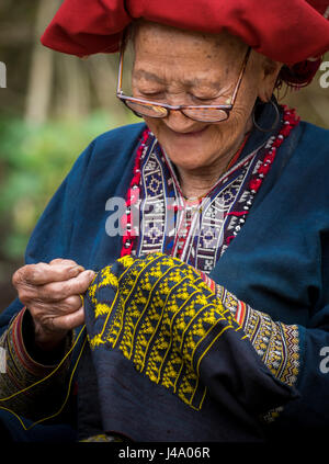 SAPA, VIETNAM - ca. SEPTEMBER 2014: alte Frau aus der roten Dao Minderheit stricken in Ta Phin Dorf in der Nähe von Sapa, Nord-Vietnam. Stockfoto