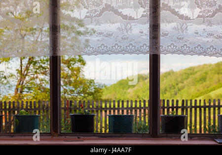 Innenraum eines Dorfes Haus Terrasse, Blick auf Windows und Blumenvasen, Stickerei auf der Oberseite als Dekoration, traditionelle handgefertigte Kunst aus Serbien. Stockfoto