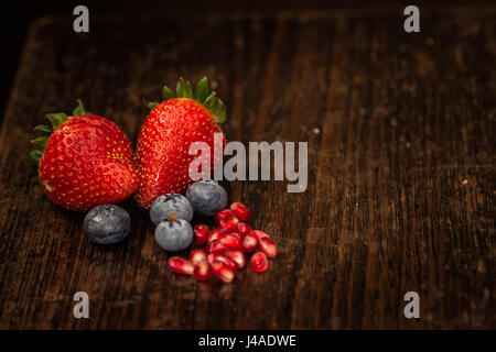 frisch gepflückt Bauernhof Erdbeeren Blaue Beeren Closeup mit Granatapfelkernen mit Textfreiraum Stockfoto