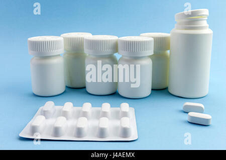 Pillen-Boote mit weißen Tabletten von verschiedenen Arten auf blauem Hintergrund Stockfoto