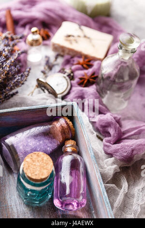 Flasche mit aromatischen Lavendel-Öl und Meersalz in einer Holzkiste, eine Flasche Parfüm, ein Bouquet von Lavendel, Stück Seife und eine Vintage Taschenuhr. Stockfoto