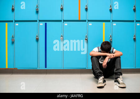 Junge sitzt allein ruhenden Kopf auf seinen Armen Stockfoto