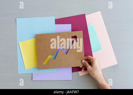 Hand zu halten, zeigt sich der Pfeil auf dem Papier grauer Hintergrund Stockfoto