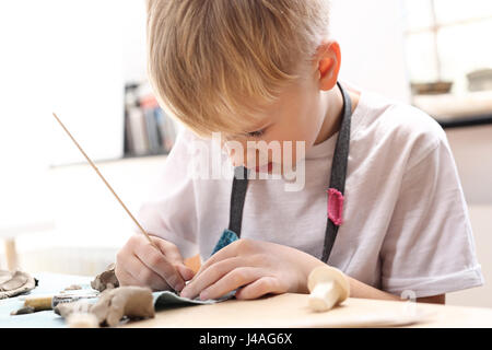 Keramik-Kurs für Kinder. Der junge ist aus Ton bei einem Kunststoff Workshop krallt. Außerschulische Aktivitäten, Keramik. Stockfoto