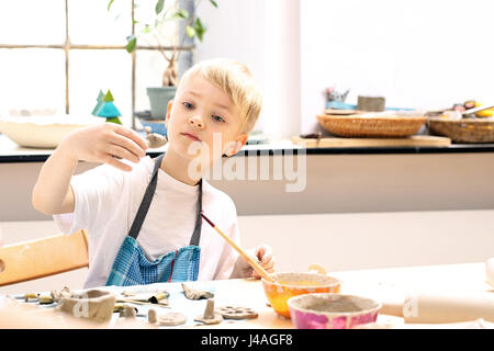 Keramik-Kurs für Kinder. Der junge ist aus Ton bei einem Kunststoff Workshop krallt. Außerschulische Aktivitäten, Keramik. Stockfoto