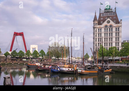 Weiße Haus Gebäude und Boote vertäut im historischen alten Hafengebiet der Oude Haven, Rotterdam, Niederlande, mit Willemsbrug im Hintergrund. Stockfoto