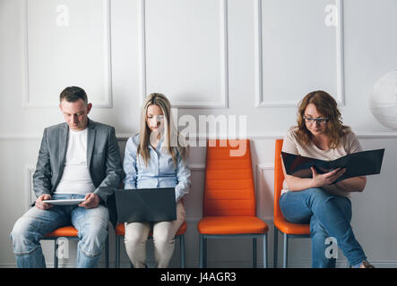 Gruppe von jungen kreativen Menschen sitzen auf Stühlen im Wartezimmer Stockfoto