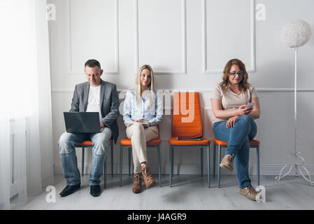 Gruppe von jungen kreativen Menschen sitzen auf Stühlen im Wartezimmer Stockfoto