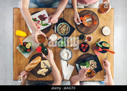 Ansicht von oben, Gruppe von Menschen sitzen am Holztisch mit Essen, ein Getränk Stockfoto