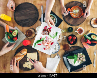 Ansicht von oben, Gruppe von Personen, die an den hölzernen Tisch essen Stockfoto