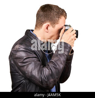 Seitliche Ansicht von einem jungen Mann mit einer Lederjacke hält eine Vintage-Kamera, ein Foto - isoliert. Stockfoto
