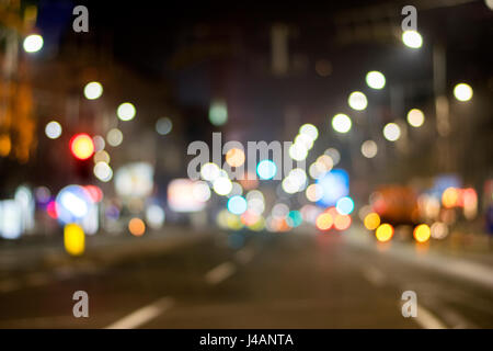 Nacht Blick auf die Stadt in Unschärfe. Stadtstraße unscharfen Foto. Streetlife-Bokeh-Bild. Straßenansicht mit Fußgänger und Autos defokussierten Bild. Straße in Großstadt Bok Stockfoto