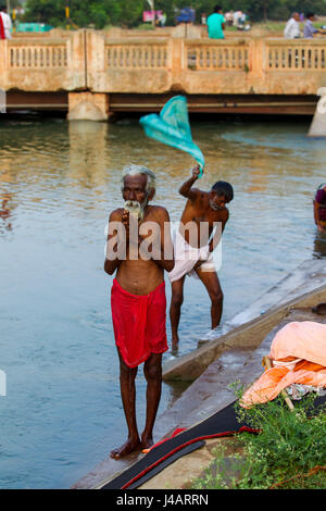 Alte indische Pilgrin beten bei Sonnenuntergang, Tungabhadra Canal, Hospet, Karnataka, Indien Stockfoto