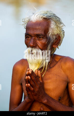 Alte indische Pilgrin beten bei Sonnenuntergang, Tungabhadra Canal, Hospet, Karnataka, Indien Stockfoto