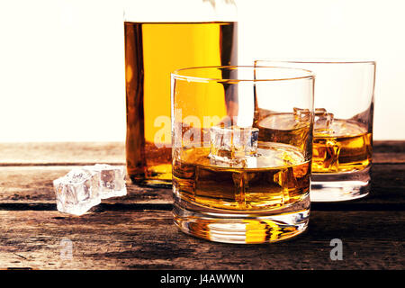 Whiskeygläser und eine Flasche auf Holztisch vor weißem Hintergrund Stockfoto